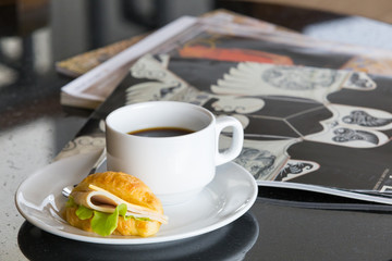 Delicious sanwich and coffee in dish on table