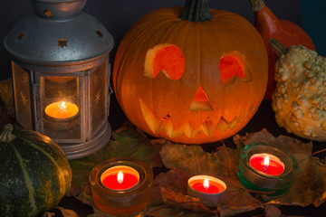 Halloween Jack o Lantern, among autumn leaves, lamps and candles