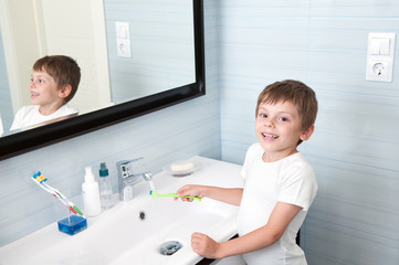 Fototapeta premium handsome healthy boy washing toothbrush over washbasin