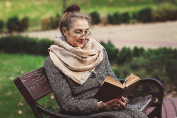 Счастливая старшая женщина, чтение книги в осеннем парке © prohor08