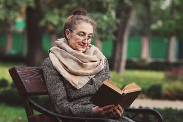 Счастливая старшая женщина, чтение книги в осеннем парке © prohor08