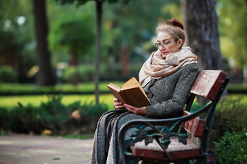 Счастливая старшая женщина, чтение книги в осеннем парке © prohor08