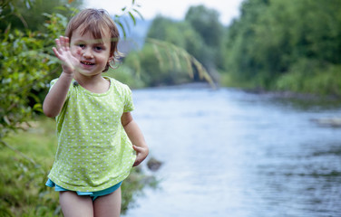 Naklejka premium Little girl having fun by river at summer (Holiday, rest, happy childhood, games, nature concept)