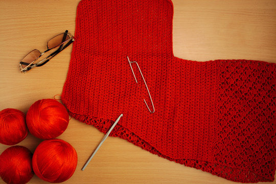 needlework, knitting needles and crochet, jacket of terracotta thread, glasses