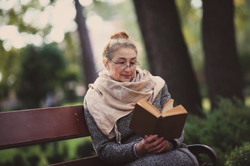 Счастливая старшая женщина, чтение книги в осеннем парке © prohor08