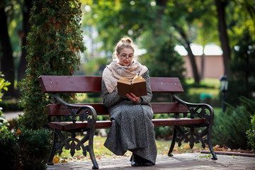 Счастливая старшая женщина, чтение книги в осеннем парке © prohor08