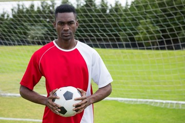 Portrait of serious confident male soccer player holding ball