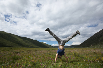 woman doing a handstand on mountain meadow