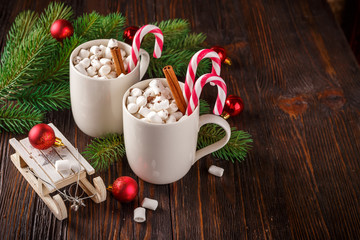 Two cups with small marshmallows on a dark wooden background