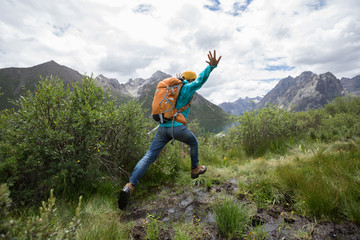 Naklejka na ściany i meble backpacking woman jumping in mountains
