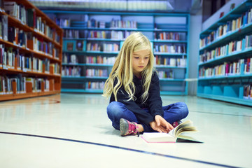 Child girl with book in public library