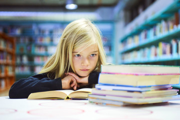 Child girl with book in public library