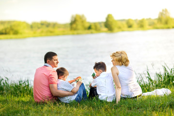 happy family on a walk in a beautiful evening park, sitting on the lake and talking.