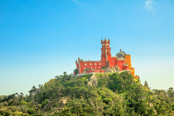 Aerial view of colorful Pena Palace on top of a hill above Sintra in asunny day with blue sky. Panorama of Palacio da Pena, a National Monument, Unesco Heritage and one of Seven Wonders of Portugal.