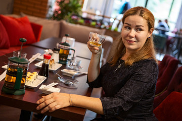 One pretty woman sitting in restaurant and drinking tea