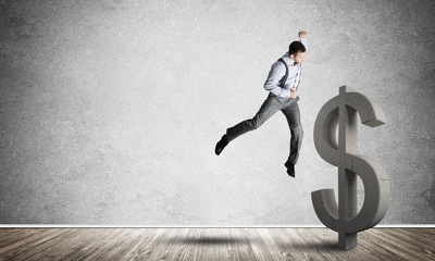 Determined banker man in empty concrete room breaking dollar figure