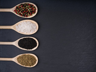 Exotic spices in wooden spoons, on a black background