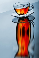 Cup of tea with plate on the reflective surface.Creative reflection.Gradient background