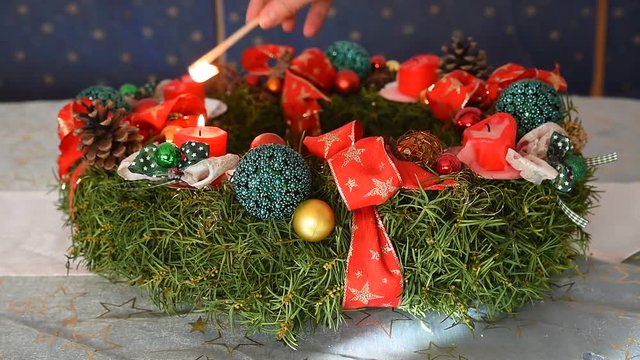 Frau z&uuml;ndent Kerzen am selbstgemachten Adventskranz an