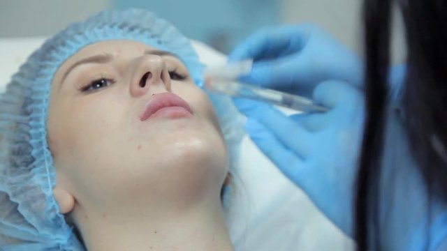 The cosmetic girl smoothes botox in the lips of the girl after the injection. Lip augmentation procedure