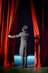 the actor in a tuxedo opens the theater curtain