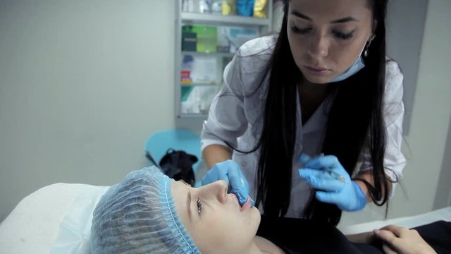 The cosmetic girl smoothes botox in the lips of the girl after the injection. Lip augmentation procedure
