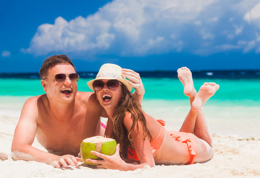 happy young couple lying and having fun on a tropical beach