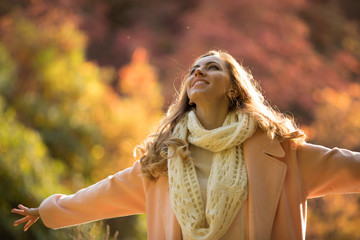 Happy and cheerful woman enjoying autumn, she raise hands