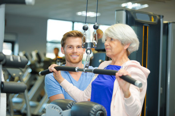 Fototapeta na wymiar personal trainer with elderly woman in gym