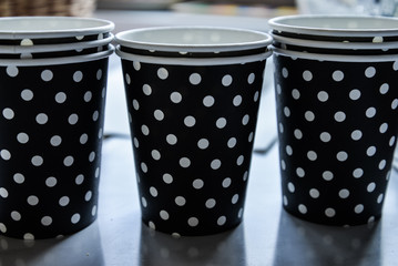 Paper cups in black and white polka dots. Disposable paper cup for coffee and hot drinks.
