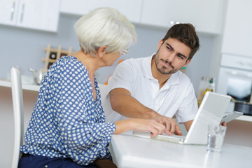 Obraz premium young man and his grandma working together on laptop