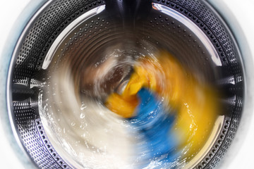 View inside the washing machine while washing laundry. Splashing water.