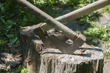 Old used weathered wooden axes stuck on wooden log for splitting wood into farmyard