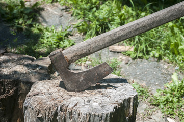 Old used weathered wooden axes stuck on wooden log for splitting wood into farmyard
