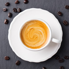 Coffee espresso in white cup on black slate background. Copy space. Top view