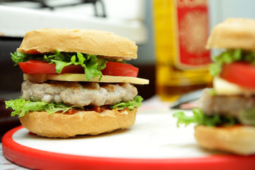 Cooking of burgers with veal, red tomatoes, lettuce, cheese and sauce in the home kitchen