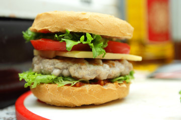 Cooking of burgers with veal, red tomatoes, lettuce, cheese and sauce in the home kitchen