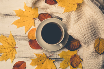 Autumn, yellow and orange fall leaves, hot cup of tea, warm scarf on wooden rustic background