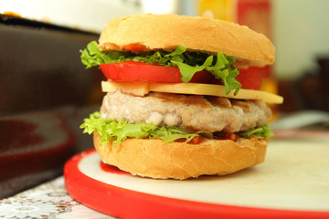 Cooking of burgers with veal, red tomatoes, lettuce, cheese and sauce in the home kitchen