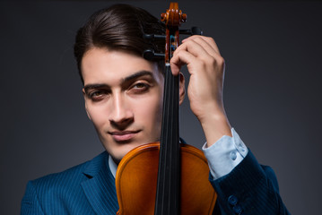 Young man playing violin in dark room