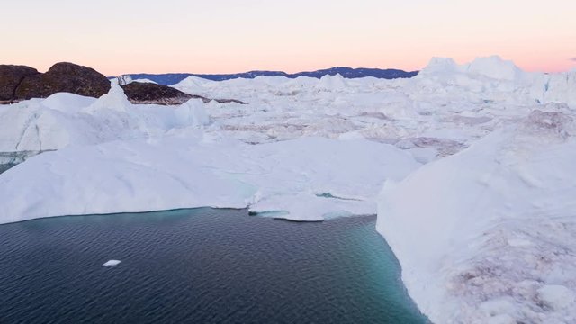 Icebergs in Greenland - Ice and Iceberg floating in Ilulissat icefjord. Icebergs from melting glacier in the arctic. Aerial video global warming and climate change concept.