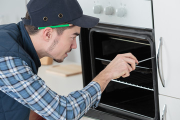 Fototapeta na wymiar young repairman in overall installing brand new oven in kitchen