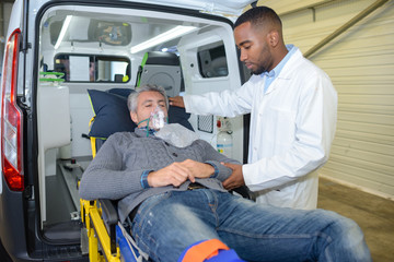 Man wearing oxygen mask being loaded into ambulance © auremar
