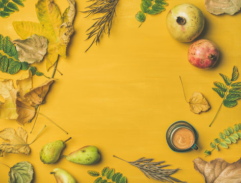 Fall background, texture, pattern. Flat-lay of Autumn harvest fruit, espresso cup and leaves over mustard yellow table, top view, copy space. Pomegranates, pears. Thanksgiving day concept