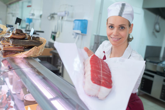 smiling female butcher holding meat