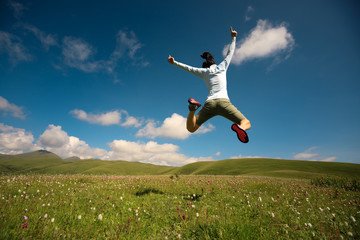 jumping woman have fun in a mountain peak meadow
