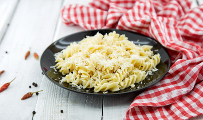 Fusilli pasta with grated parmesan cheese on rustic wooden table. Italian cuisine. Healthy homemade food