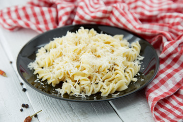 Fusilli pasta with grated parmesan cheese on rustic wooden table. Italian cuisine. Healthy homemade food