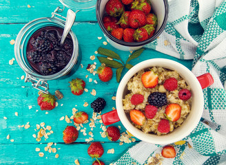 Organic cottage cheese with blackberry, strawberry and raspberry in a white ceramic bowl on the kitchen table. Dairy products for the breakfast. Healthy food concept. Top view
