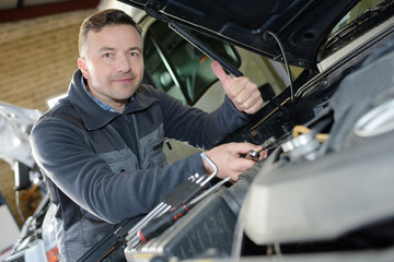 Fototapeta na wymiar smiling mechanic working on an engines car in a garage